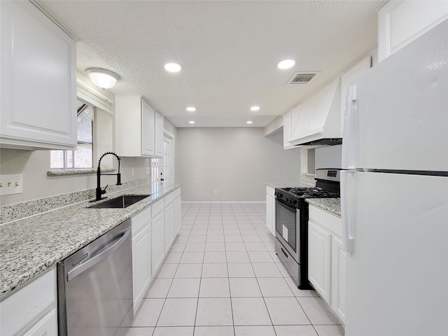 kitchen featuring sink, white cabinetry, light stone counters, appliances with stainless steel finishes, and custom range hood