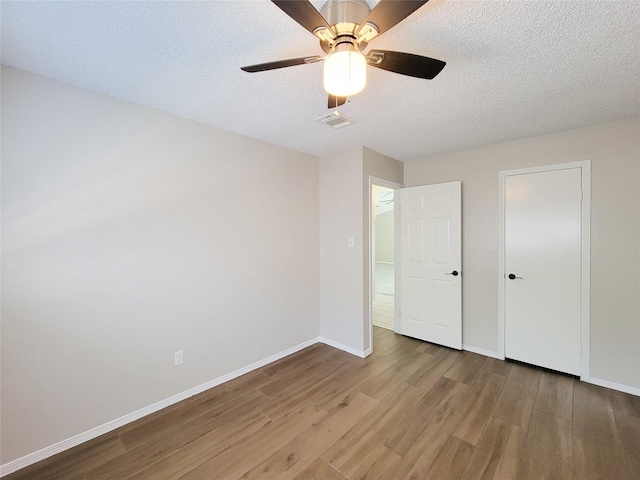 unfurnished bedroom with ceiling fan, wood-type flooring, and a textured ceiling