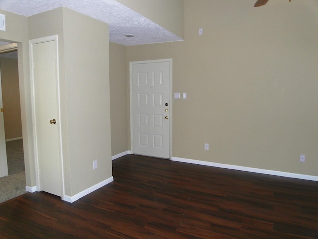 spare room with a textured ceiling, dark wood-type flooring, and ceiling fan