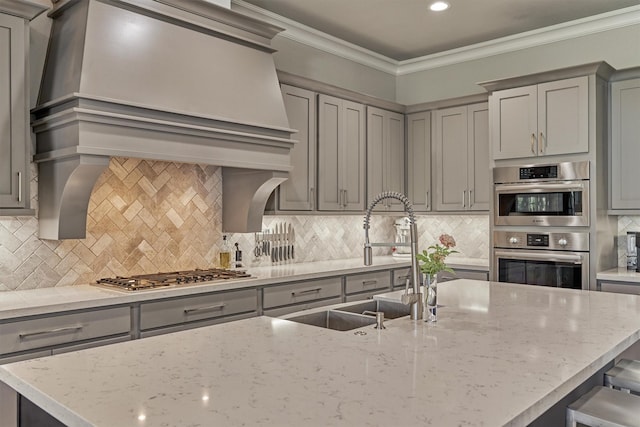 kitchen with sink, gray cabinets, appliances with stainless steel finishes, light stone counters, and tasteful backsplash