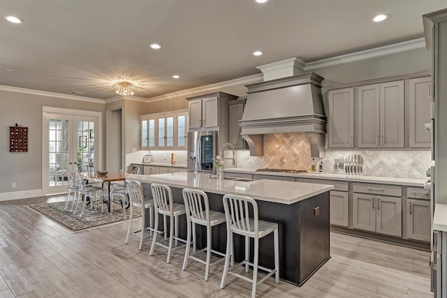 kitchen featuring sink, light hardwood / wood-style flooring, a breakfast bar, a kitchen island with sink, and french doors