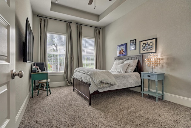 bedroom with ceiling fan, carpet flooring, and a raised ceiling