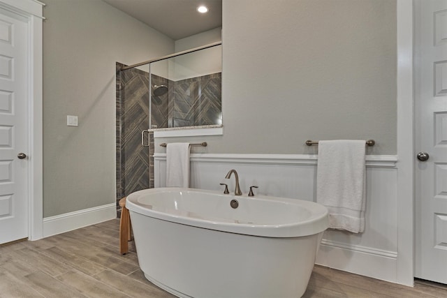 bathroom with hardwood / wood-style floors and shower with separate bathtub