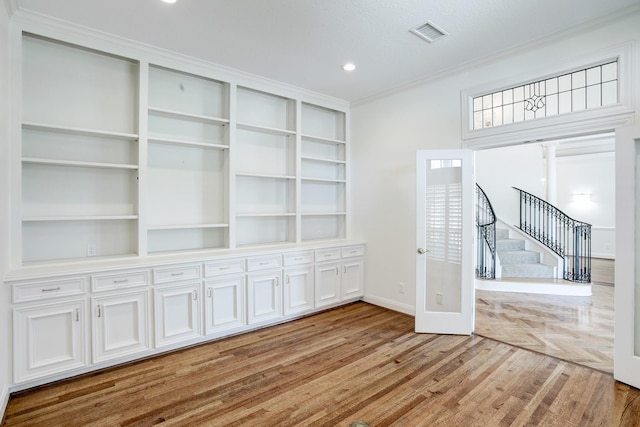 5419 W Bayshore Dr, Bacliff, TX 77518 - unfurnished room featuring baseboards, wood finished floors, ornamental molding, stairs, and built in shelves