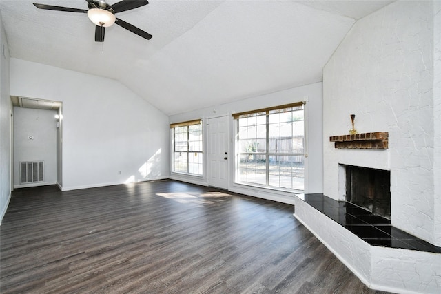 unfurnished living room with dark wood-type flooring, lofted ceiling, a textured ceiling, a large fireplace, and ceiling fan