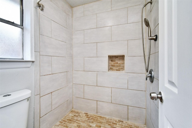 bathroom featuring a tile shower and toilet