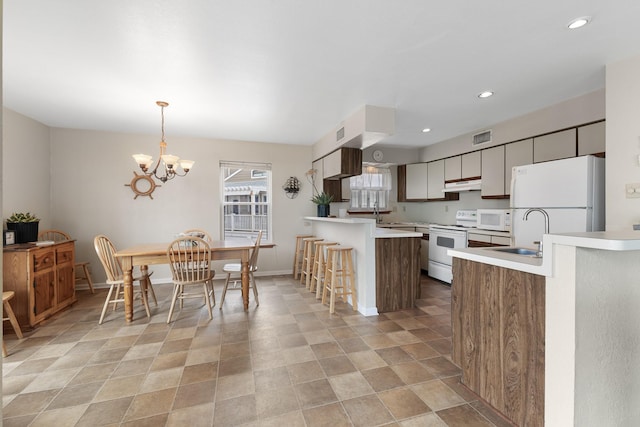 kitchen with a breakfast bar, sink, kitchen peninsula, pendant lighting, and white appliances