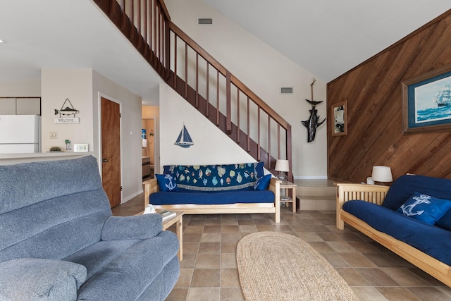 living room featuring high vaulted ceiling and wood walls