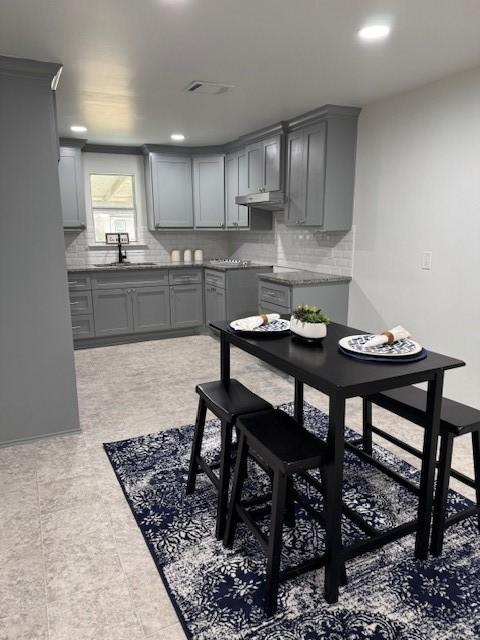 2748 Cos St, Liberty, TX 77575 - kitchen featuring gray cabinets, backsplash, under cabinet range hood, and a sink