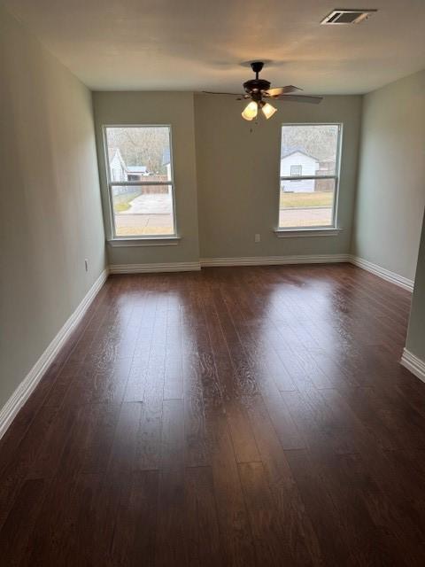 2748 Cos St, Liberty, TX 77575 - unfurnished room featuring dark wood-style floors, visible vents, baseboards, and a healthy amount of sunlight