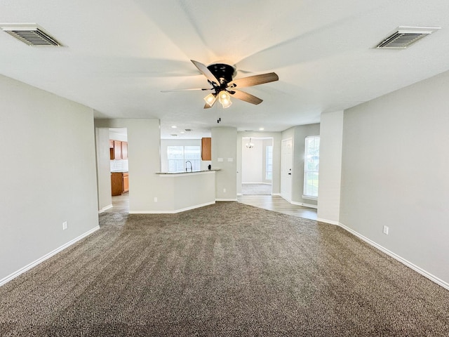 unfurnished living room with carpet flooring, a wealth of natural light, and ceiling fan