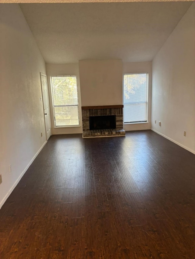 unfurnished living room with a fireplace, dark hardwood / wood-style floors, a healthy amount of sunlight, and vaulted ceiling