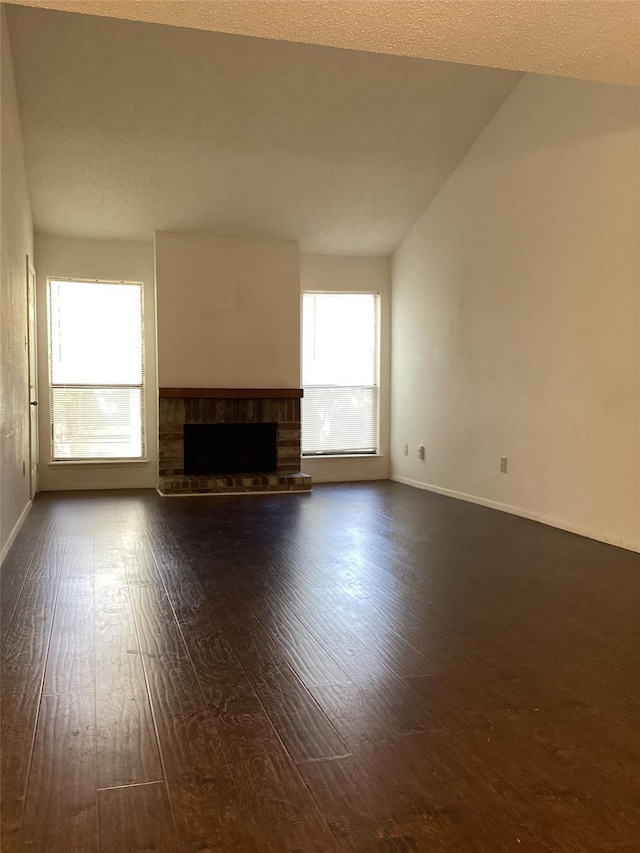 unfurnished living room featuring a brick fireplace, dark wood-type flooring, and lofted ceiling