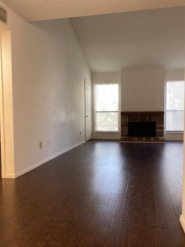 unfurnished living room with dark hardwood / wood-style floors, lofted ceiling, a fireplace, and plenty of natural light