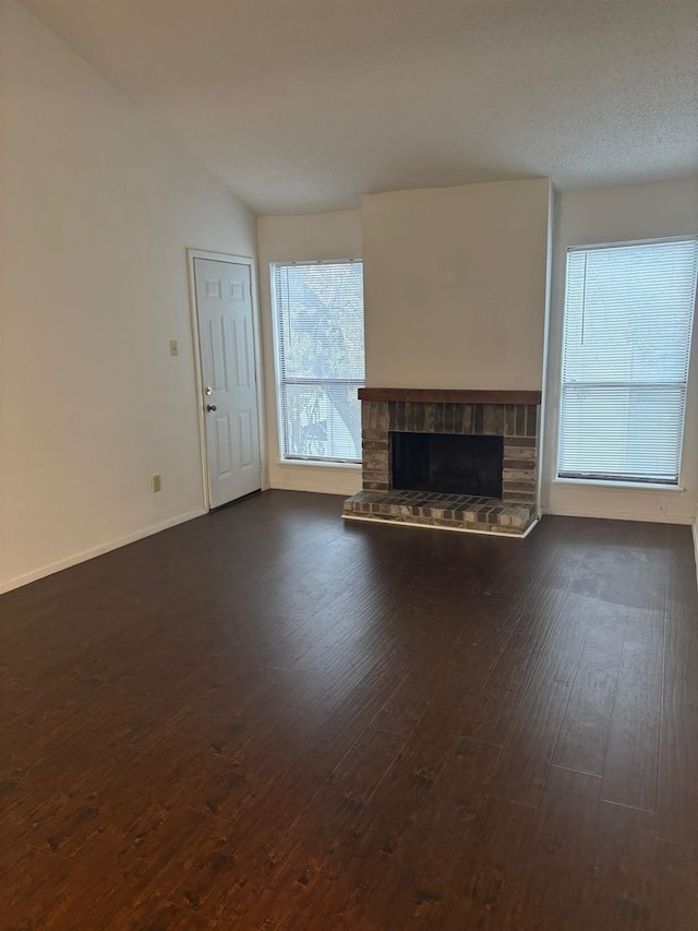 unfurnished living room featuring lofted ceiling, dark hardwood / wood-style floors, and a stone fireplace