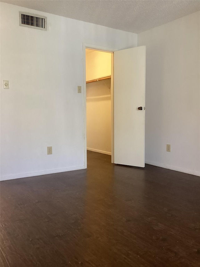 spare room with dark hardwood / wood-style floors and a textured ceiling