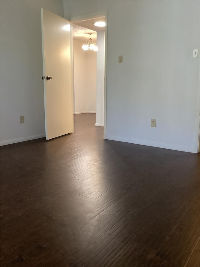 empty room featuring dark hardwood / wood-style floors and a notable chandelier