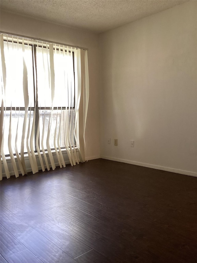 unfurnished room featuring dark hardwood / wood-style flooring and a textured ceiling