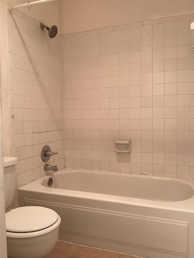 bathroom featuring tiled shower / bath combo, tile patterned floors, and toilet