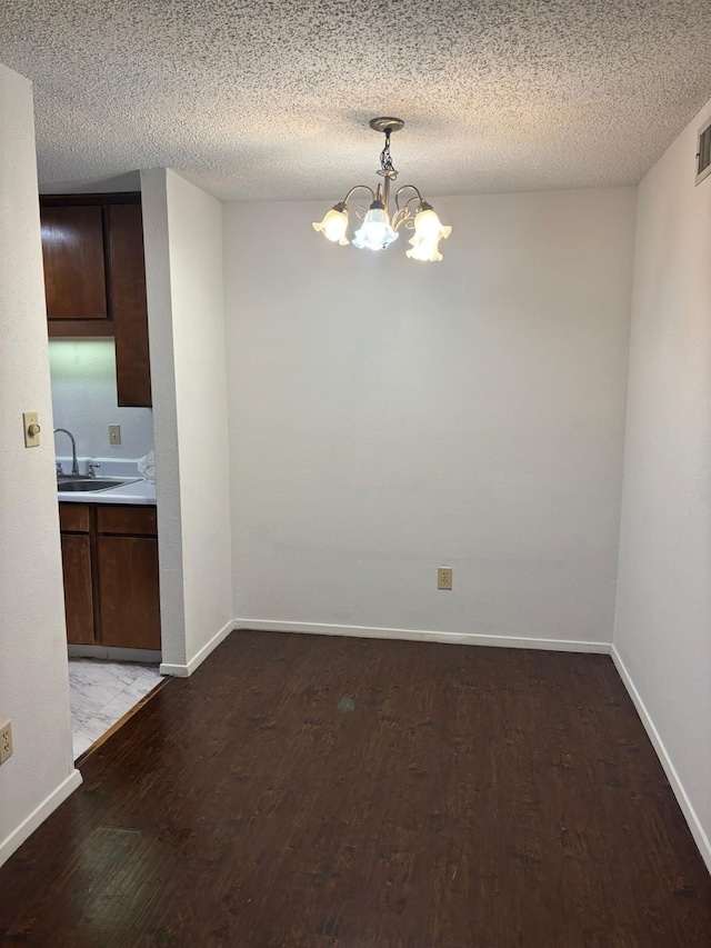 unfurnished dining area featuring sink, a textured ceiling, and a chandelier