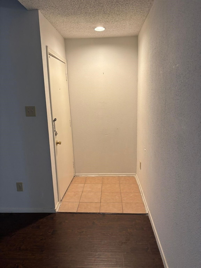 hallway with light hardwood / wood-style floors and a textured ceiling