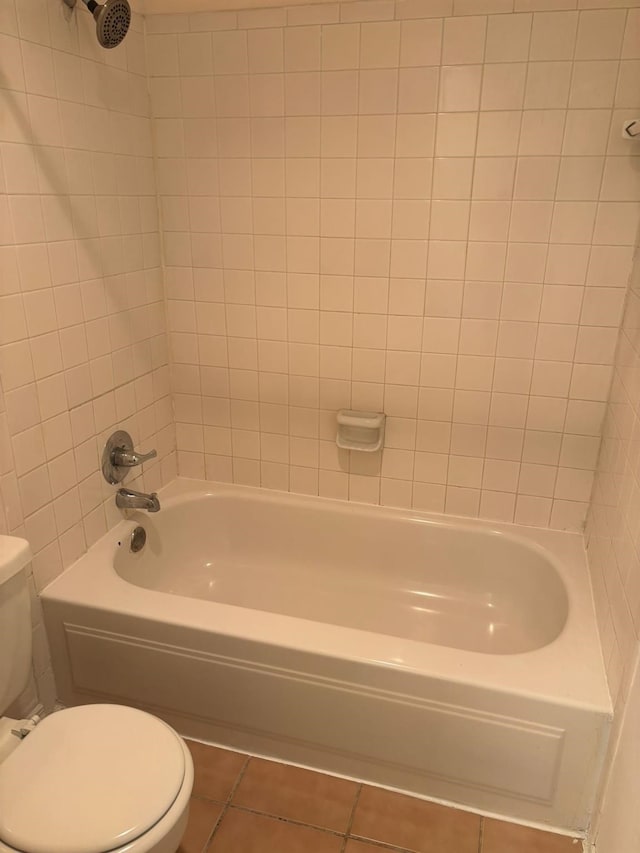 bathroom with tiled shower / bath, toilet, and tile patterned flooring