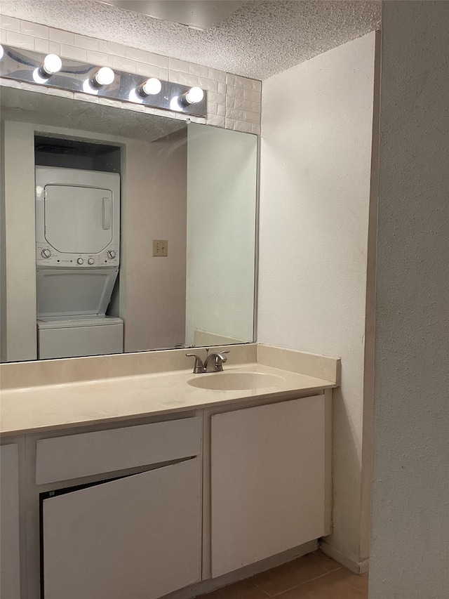 bathroom with tile patterned floors, stacked washer / dryer, a textured ceiling, and vanity