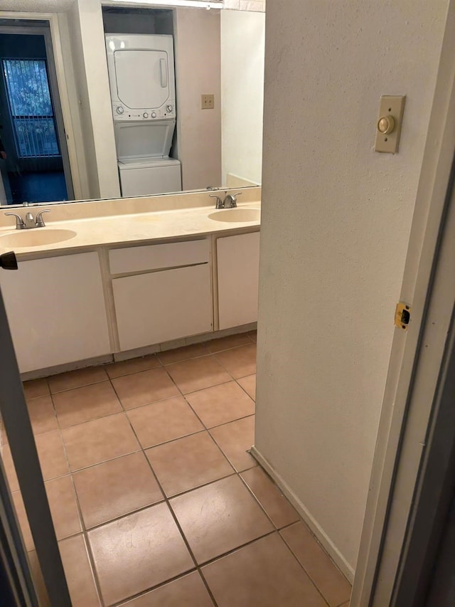 bathroom featuring stacked washing maching and dryer, tile patterned floors, and vanity