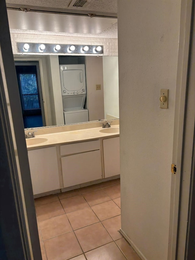 bathroom featuring stacked washer and clothes dryer, tile patterned flooring, vanity, and a textured ceiling