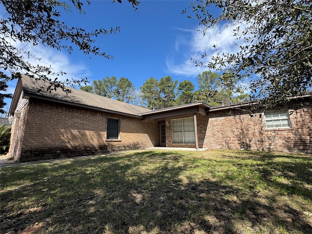 rear view of house with brick siding and a yard