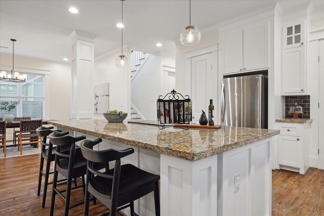 kitchen featuring white cabinetry, hanging light fixtures, stainless steel fridge, and light hardwood / wood-style floors