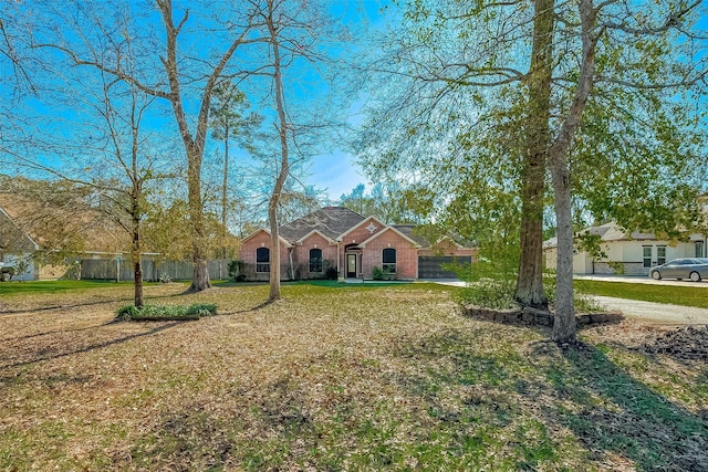 view of front of home featuring brick siding, fence, and a front lawn