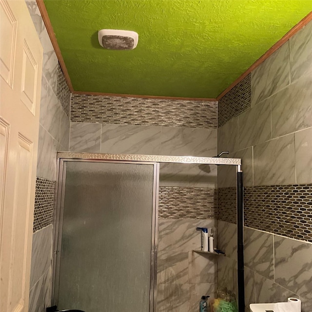 bathroom with tile walls and a shower with door