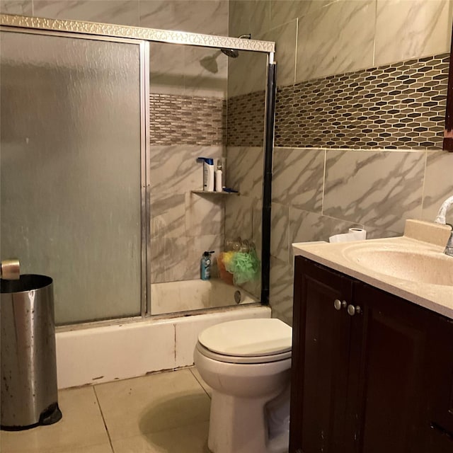 full bathroom featuring enclosed tub / shower combo, tile patterned flooring, tile walls, vanity, and toilet