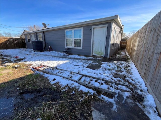 snow covered rear of property featuring central air condition unit