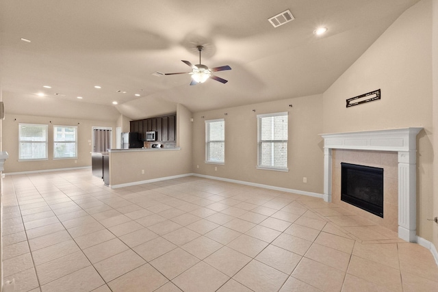 unfurnished living room with a tile fireplace, light tile patterned flooring, vaulted ceiling, and ceiling fan