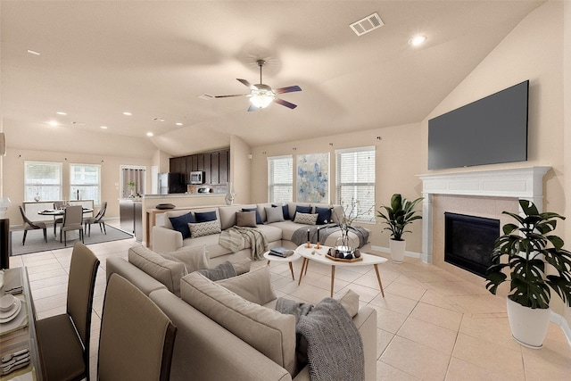 tiled living room featuring ceiling fan, lofted ceiling, and a fireplace