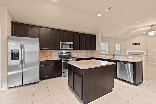 kitchen featuring lofted ceiling, sink, appliances with stainless steel finishes, dark brown cabinets, and a center island