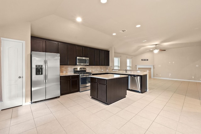 kitchen featuring vaulted ceiling, light tile patterned flooring, ceiling fan, kitchen peninsula, and stainless steel appliances