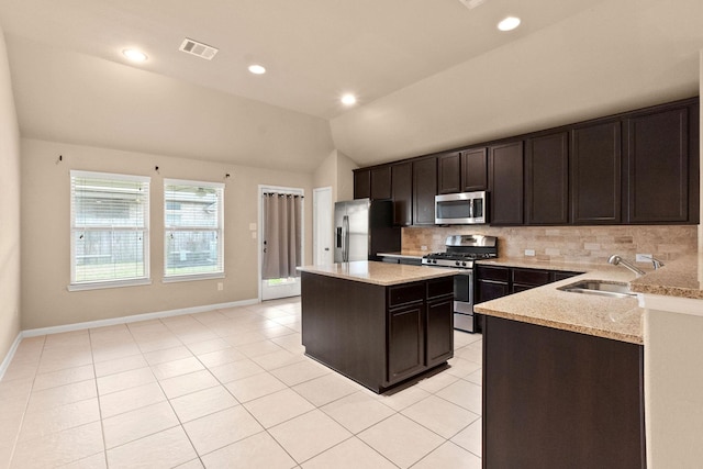 kitchen with lofted ceiling, sink, a center island, appliances with stainless steel finishes, and decorative backsplash