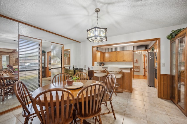 dining area with an inviting chandelier, wooden walls, and a textured ceiling