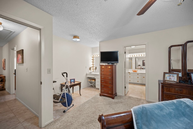 bedroom with ceiling fan, light colored carpet, ensuite bath, and a textured ceiling