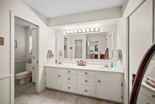 bathroom featuring tile patterned flooring, vanity, a textured ceiling, and toilet