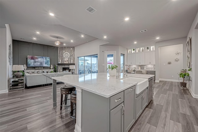 kitchen with sink, gray cabinets, a spacious island, tasteful backsplash, and light hardwood / wood-style floors