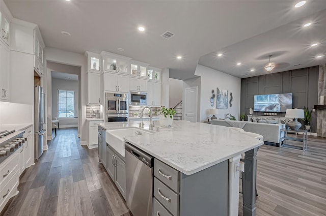 kitchen with sink, gray cabinetry, white cabinetry, stainless steel appliances, and a kitchen island with sink