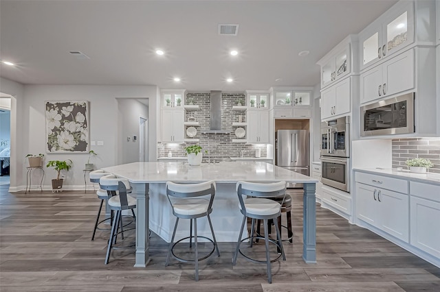 kitchen with stainless steel appliances, a kitchen island with sink, and white cabinets