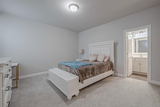 bedroom featuring sink, ensuite bath, and light colored carpet