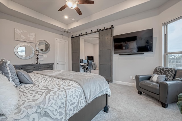 carpeted bedroom featuring a tray ceiling, a barn door, and ceiling fan