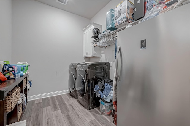 laundry room with cabinets, independent washer and dryer, and light wood-type flooring