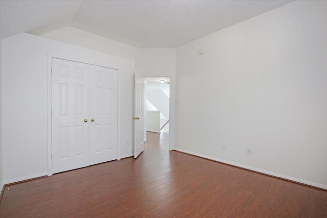 unfurnished bedroom with lofted ceiling, dark hardwood / wood-style flooring, and a closet